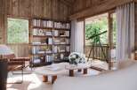 Step into a serene retreat with this stunning property, featuring a cozy interior with wooden walls and a large bookshelf.