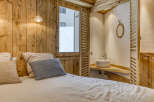 Experience rustic charm in this cozy bedroom featuring wooden paneling and a unique window design.