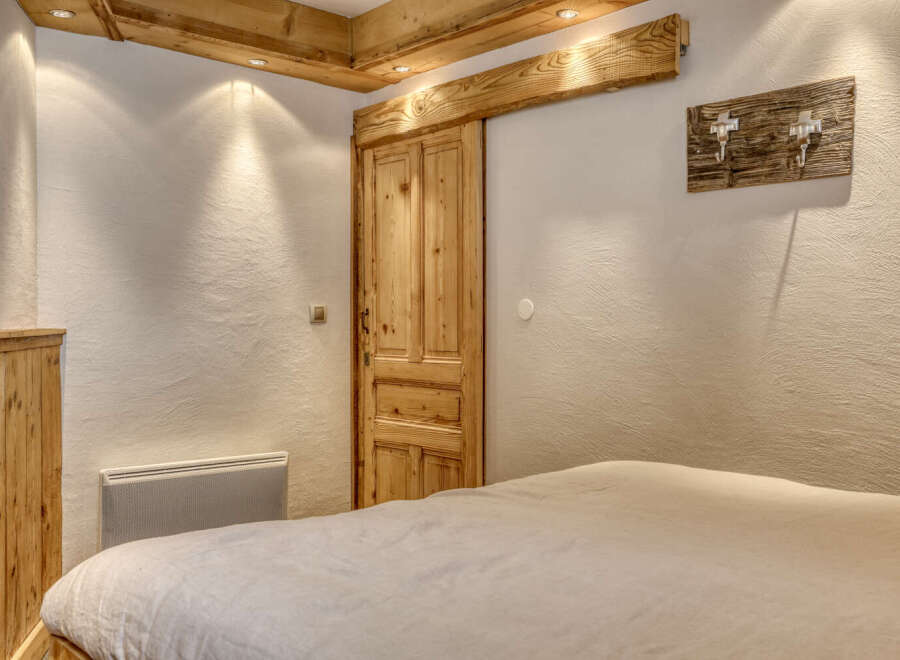 This charming bedroom features a rustic wooden door and ceiling beams, creating a warm and inviting atmosphere.