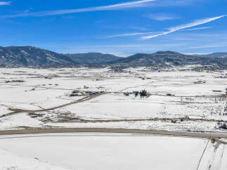 This stunning property offers breathtaking views of snow-covered fields and majestic mountains.