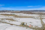 This stunning property offers a picturesque landscape with snow-covered fields and rolling hills.