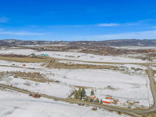 This stunning property offers a picturesque landscape with snow-covered fields and rolling hills.