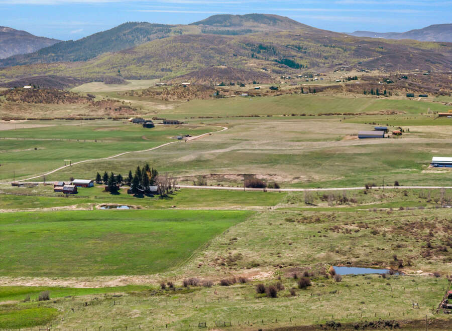 Discover a sprawling rural estate offering a picturesque landscape with rolling green fields and distant mountains.