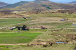 Discover a sprawling rural estate offering a picturesque landscape with rolling green fields and distant mountains.