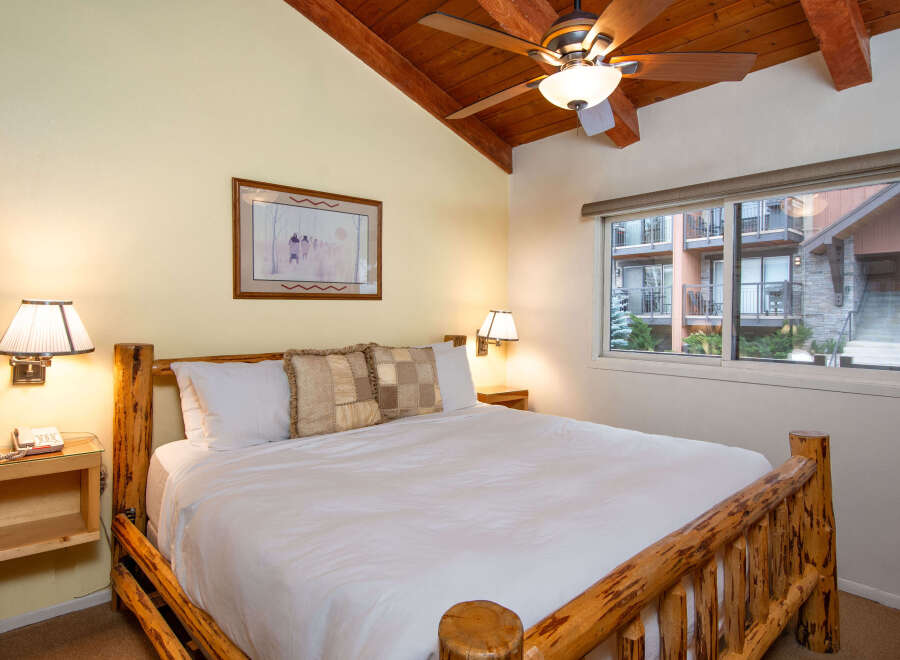 This cozy bedroom features a rustic wooden bed frame, creating a warm and inviting atmosphere.