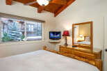 This cozy bedroom features a rustic wooden bed frame and a charming view of the snowy outdoors.