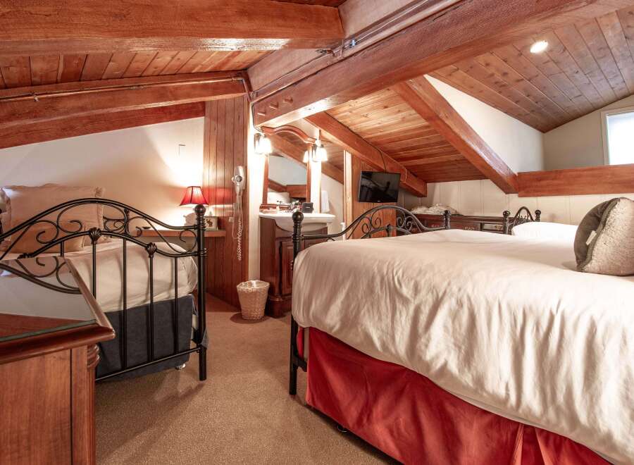 This charming bedroom features a cozy, rustic design with exposed wooden beams and a warm, inviting atmosphere.