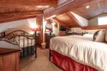 This charming bedroom features a cozy, rustic design with exposed wooden beams and a warm, inviting atmosphere.
