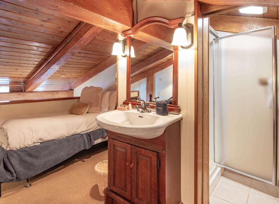 Discover the charm of this cozy bathroom, featuring a rustic wooden ceiling and a stylish vanity.