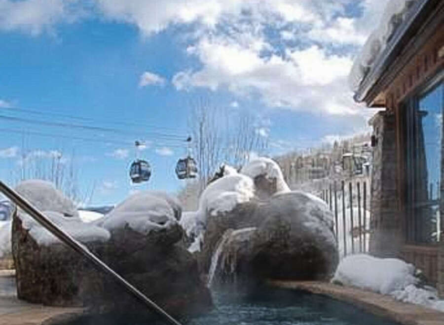 Enjoy the ultimate relaxation experience in this stunning property featuring a hot tub surrounded by snow-covered rocks.