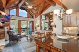 Experience luxury mountain living in this stunning condo featuring vaulted ceilings with exposed wooden beams and a wall of windows offering breathtaking views.