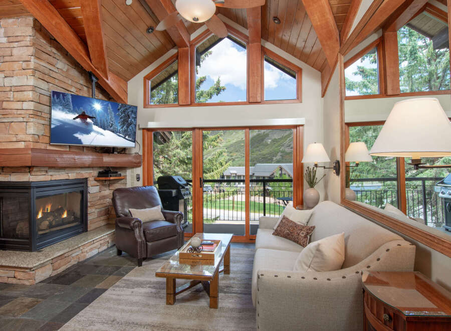 Experience mountain living in this stunning living room featuring a cozy stone fireplace and a large flat-screen TV perfect for relaxing after a day on the slopes.