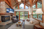 Experience mountain living in this stunning living room featuring a cozy stone fireplace and a large flat-screen TV perfect for relaxing after a day on the slopes.