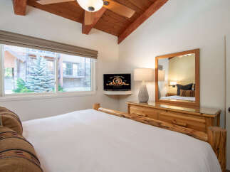 Experience rustic charm in this cozy bedroom featuring a comfortable bed with log accents and decorative pillows.