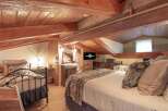 Experience rustic charm in this unique attic bedroom, featuring exposed wooden beams and a cozy, sloped ceiling.