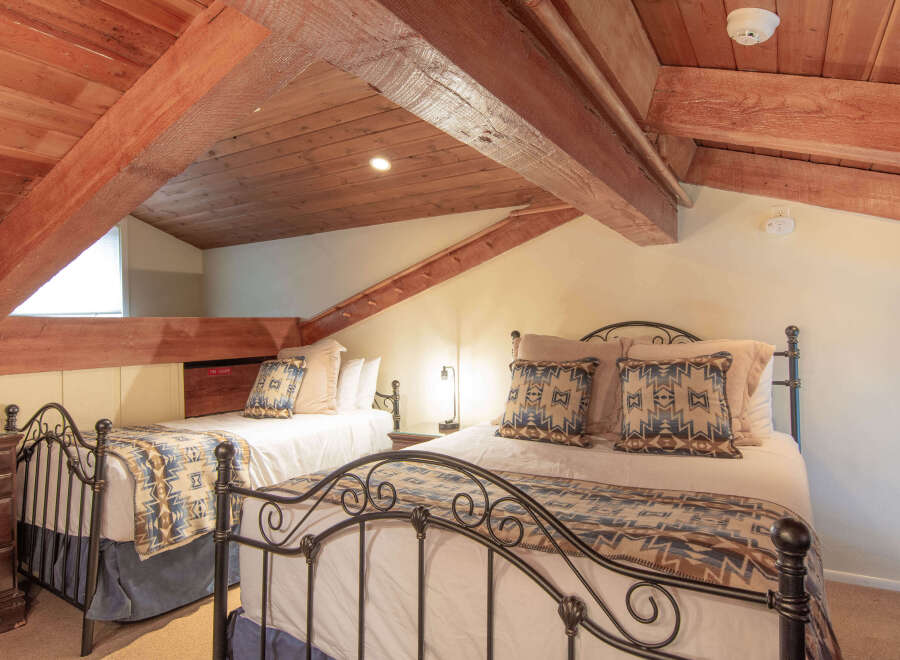 Discover this charming attic bedroom featuring two comfortable beds, perfect for accommodating guests.
