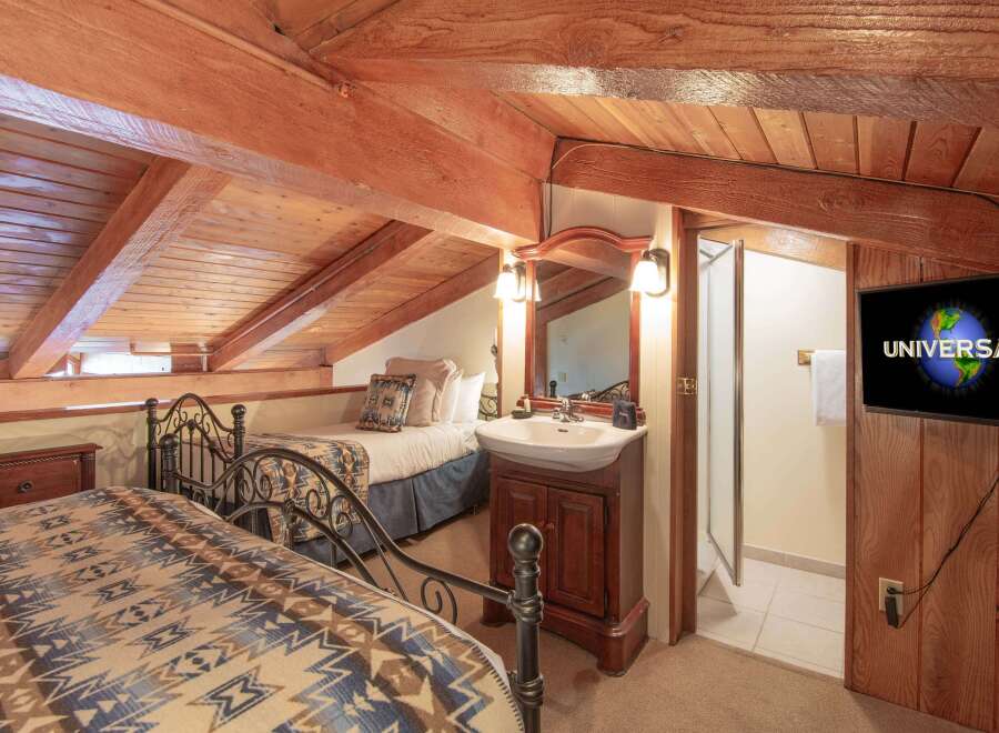 This charming attic bedroom features two cozy beds with rustic patterned blankets, perfect for a relaxing getaway.