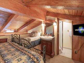 This charming attic bedroom features two cozy beds with rustic patterned blankets, perfect for a relaxing getaway.