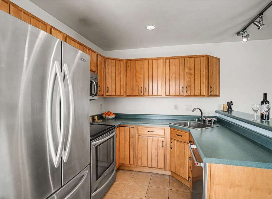 This stunning kitchen boasts modern stainless steel appliances, including a refrigerator and oven, complemented by warm wooden cabinetry.