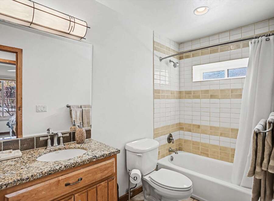 This stunning bathroom features a beautiful granite countertop and a stylish wooden vanity, offering both elegance and functionality.