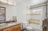 This stunning bathroom features a beautiful granite countertop and a stylish wooden vanity, offering both elegance and functionality.