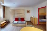 Discover this cozy apartment featuring a comfortable living area with a pull-out sofa and vibrant red cushions.
