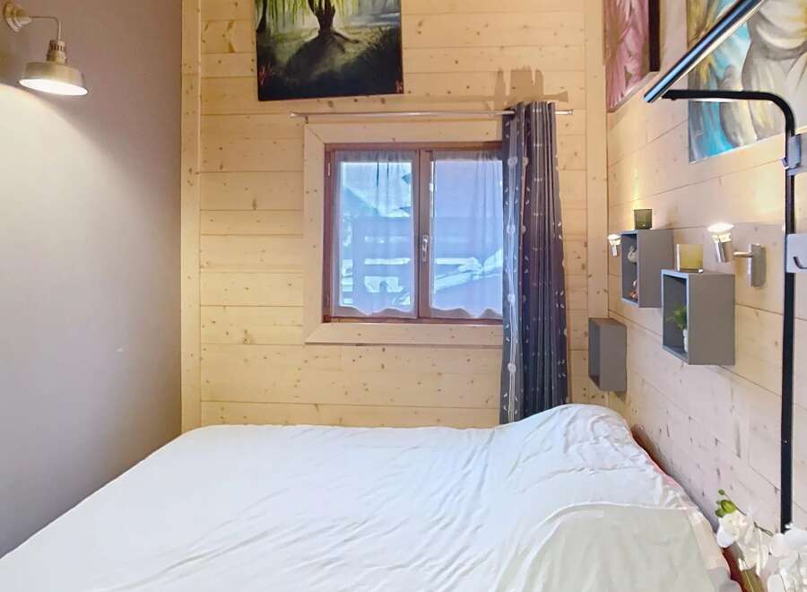 Discover the charm of this cozy bedroom, featuring a warm wooden interior and a comfortable bed.