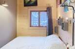 Discover the charm of this cozy bedroom, featuring a warm wooden interior and a comfortable bed.