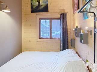 Discover the charm of this cozy bedroom, featuring a warm wooden interior and a comfortable bed.