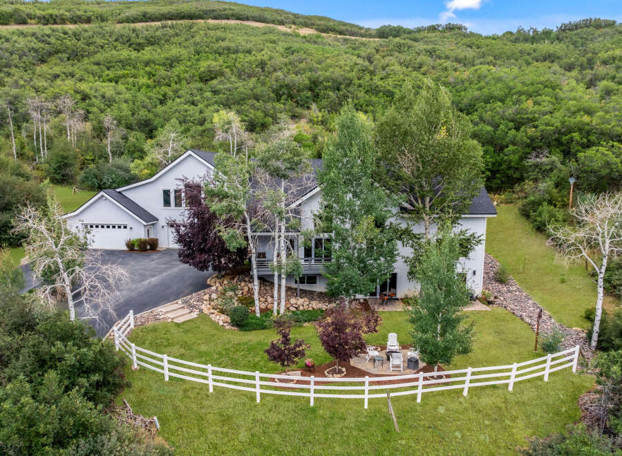 This stunning property boasts a modern, two-story home with a spacious garage, nestled in a serene, tree-filled landscape.