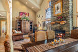 This stunning living room boasts a rustic charm with its stone fireplace and exposed wooden beams.