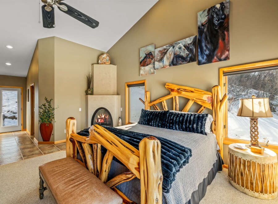 Experience rustic luxury in this stunning bedroom, featuring a unique log-style bed frame and a cozy fireplace.