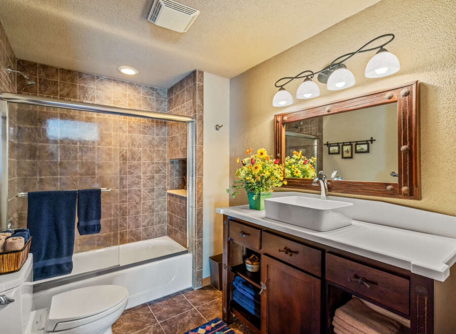 This beautiful bathroom features a modern vanity with a vessel sink and ample storage.