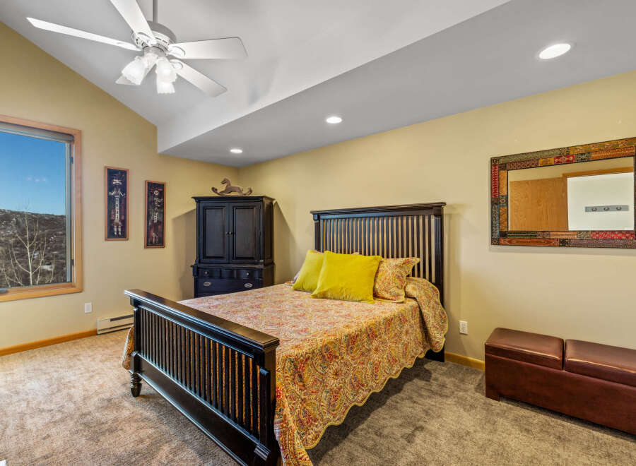 This inviting bedroom features a comfortable bed with a decorative quilt and vibrant yellow pillows, creating a cozy atmosphere.