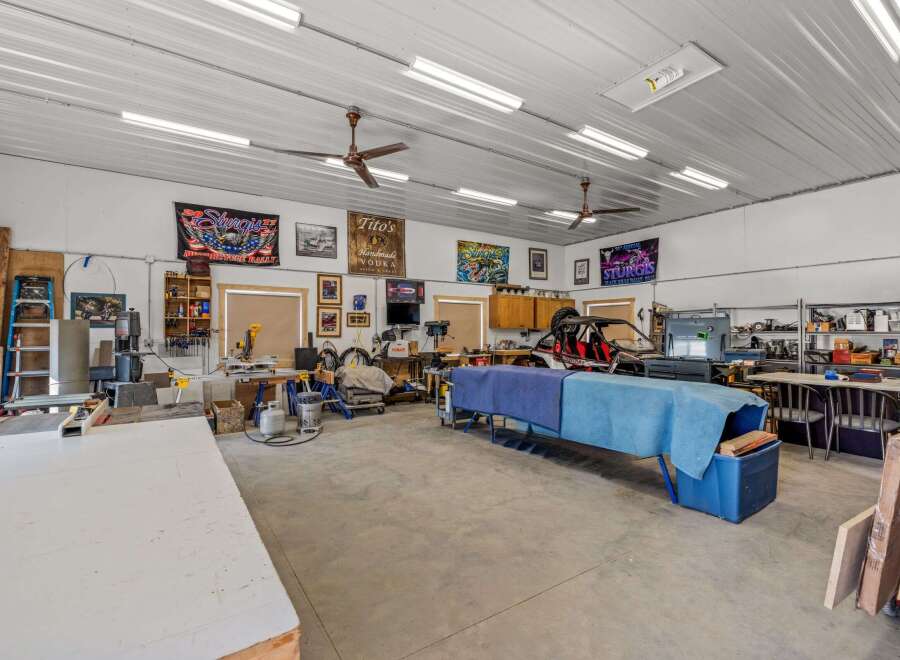 This spacious workshop offers ample room for projects and hobbies, featuring a well-lit interior with multiple ceiling lights and fans.