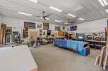 This spacious workshop offers ample room for projects and hobbies, featuring a well-lit interior with multiple ceiling lights and fans.