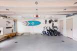 This spacious garage offers ample storage and recreational space, featuring two surfboards mounted on the wall and a row of electric bikes ready for adventure.