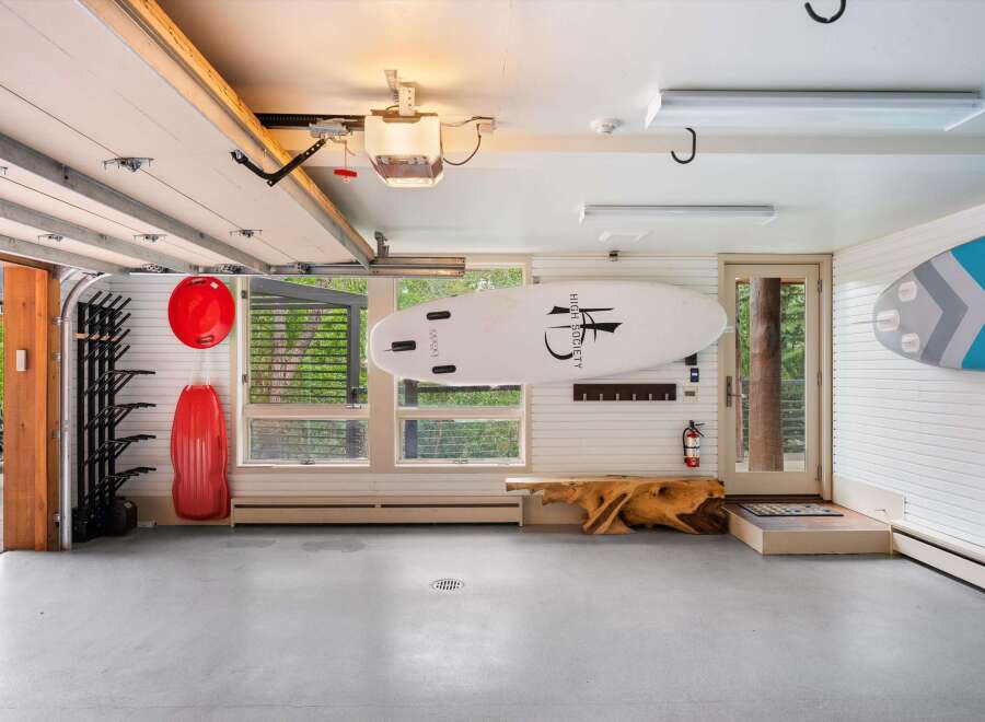 This spacious garage offers ample storage for your recreational gear, featuring a dedicated rack for surfboards or paddleboards and additional wall-mounted storage.