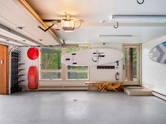 This spacious garage offers ample storage for your recreational gear, featuring a dedicated rack for surfboards or paddleboards and additional wall-mounted storage.
