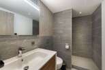 Step into a modern bathroom oasis, featuring sleek gray tile and natural wood accents.