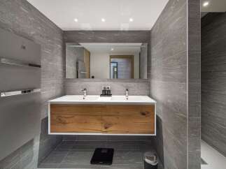 This modern bathroom boasts a sleek design with its gray tiled walls and wooden vanity.
