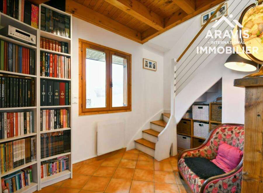 Discover the charm of this inviting property, featuring a cozy reading nook with a floral armchair and a well-stocked bookshelf.