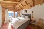 Experience the charm of this stunning bedroom with its exposed wooden beams and breathtaking mountain views.