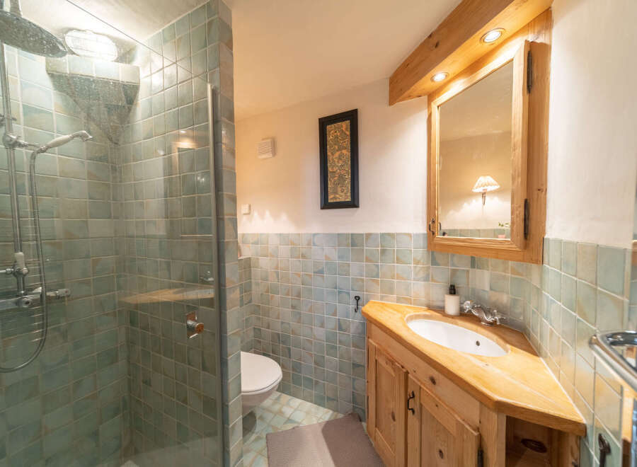 Step into this charming bathroom, featuring a unique corner vanity crafted from warm wood.