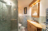 Step into this charming bathroom, featuring a unique corner vanity crafted from warm wood.