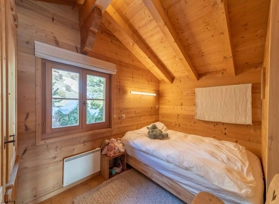 This cozy bedroom features beautiful wooden walls and a sloped ceiling, creating a warm and inviting atmosphere.