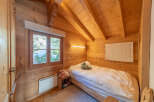 This cozy bedroom features beautiful wooden walls and a sloped ceiling, creating a warm and inviting atmosphere.
