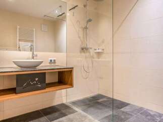Step into a modern bathroom oasis! This stunning space features a sleek glass-enclosed shower, a stylish floating vanity with a vessel sink, and elegant tile flooring.