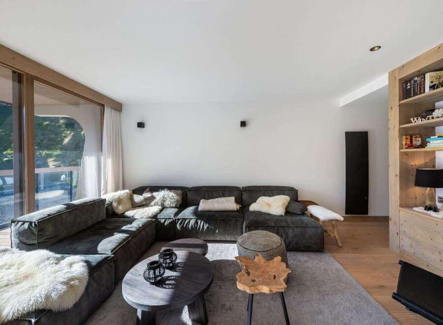 Experience luxury living in this stunning property! This modern living room features a spacious sectional sofa, cozy sheepskin rugs, and stylish coffee tables.