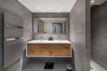 This modern bathroom boasts a sleek design with gray tiled walls and a stylish wooden vanity.